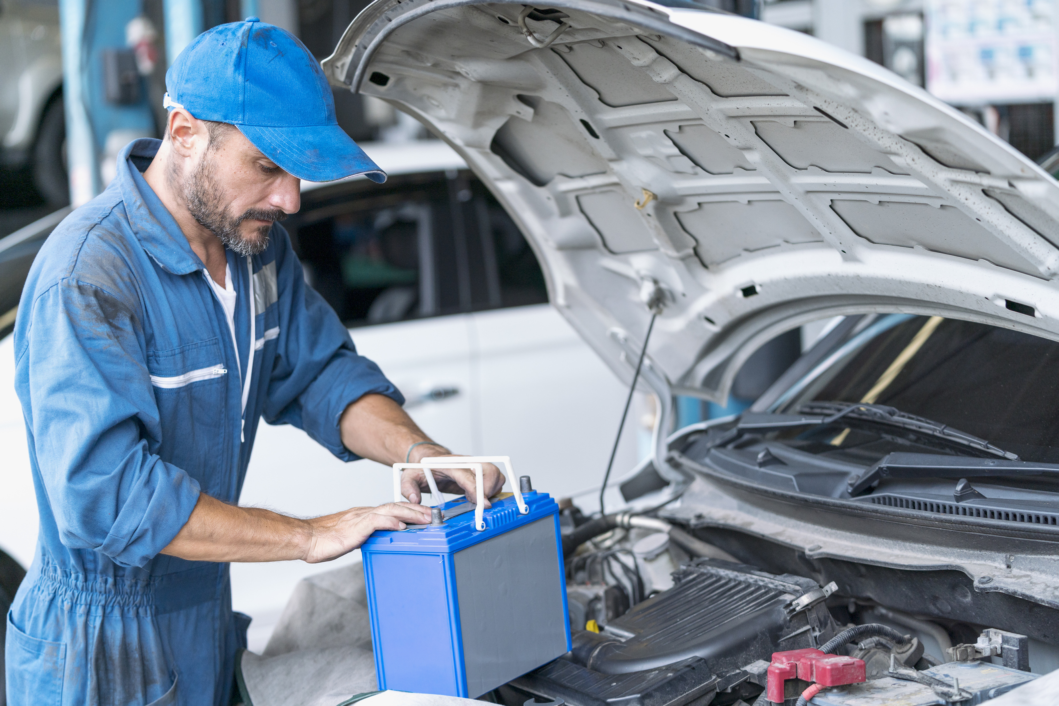 Car repairs. Auto services and Small business concepts. A car mechanic is replacing the battery in an auto repair center.